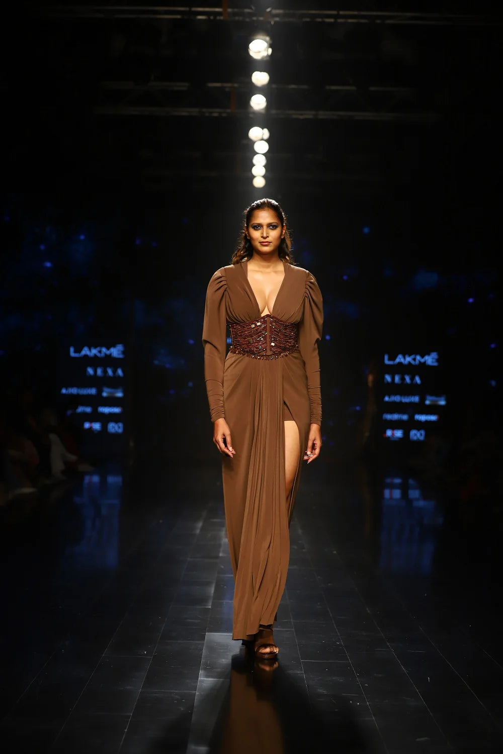 Dark tan designer dress with thigh-high slit and embellished corset waist on runway