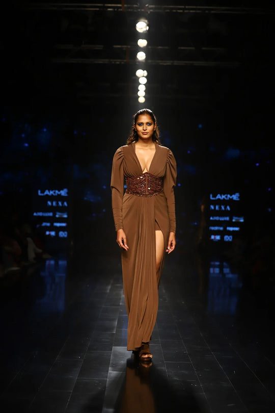 Dark tan designer dress with thigh-high slit and embellished corset waist on runway